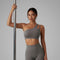 Femme tenant une barre de Pole Dance et portant une brassière de Pole Dance grise