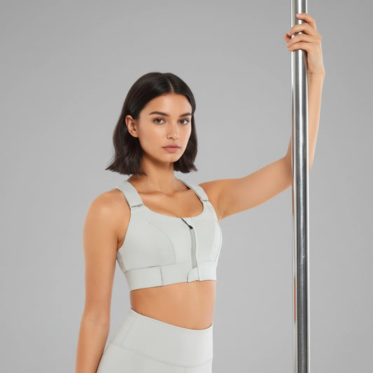 Femme tenant une barre de pole dance et portant une brassière de pole dance grise