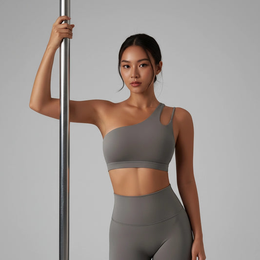 Femme tenant une barre de Pole Dance et portant une brassière de Pole Dance grise