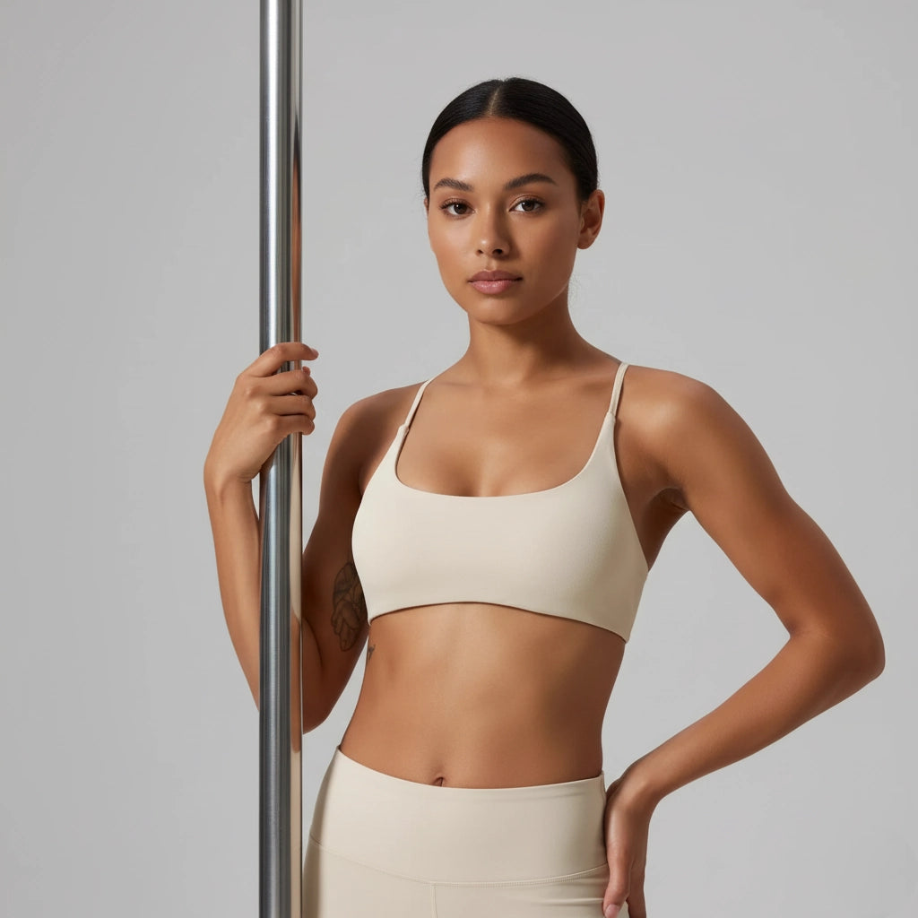 Femme tenant une barre de pole dance et portant une brassière de Pole Dance beige