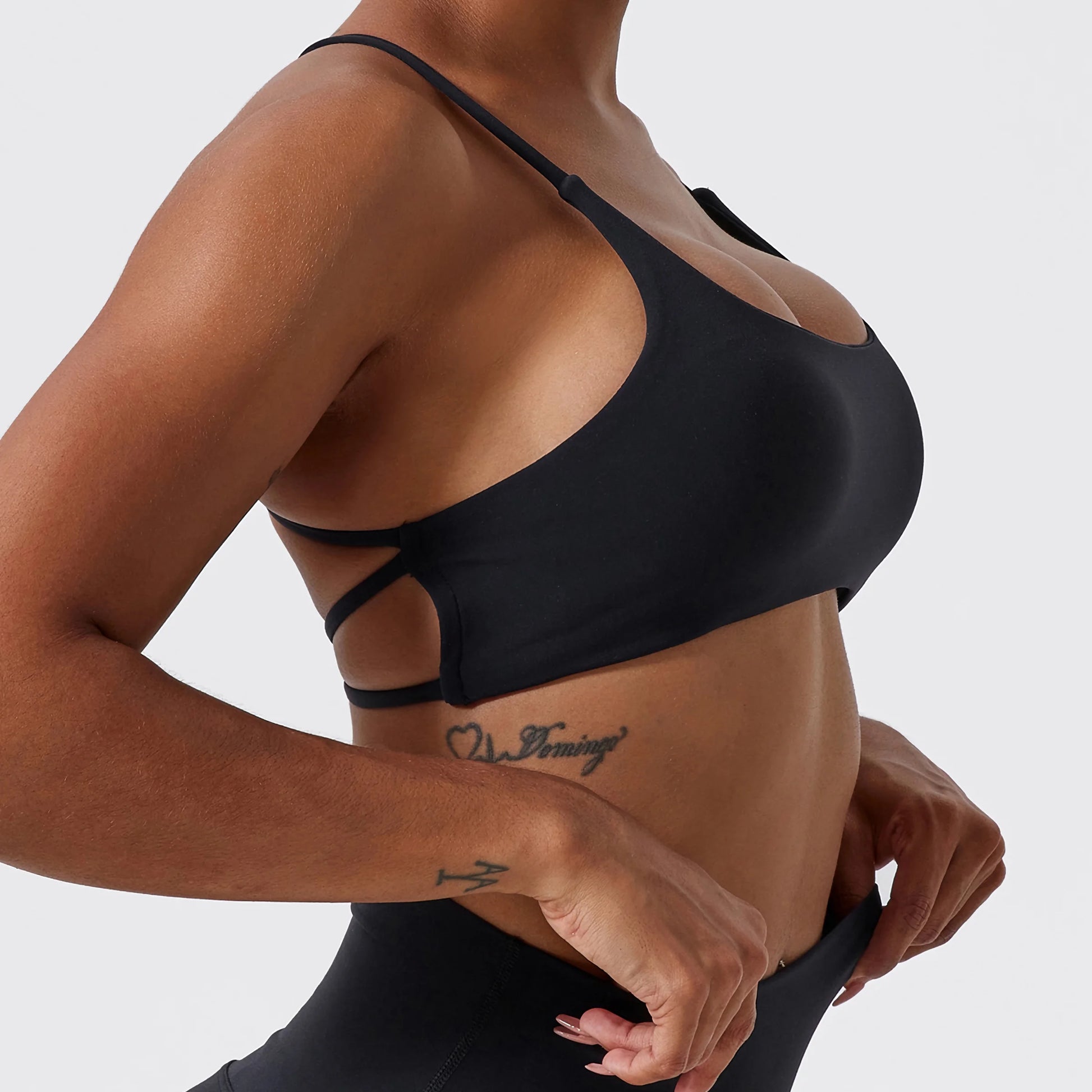 Vue de côté d'une Femme portant une brassière de Pole Dance noire