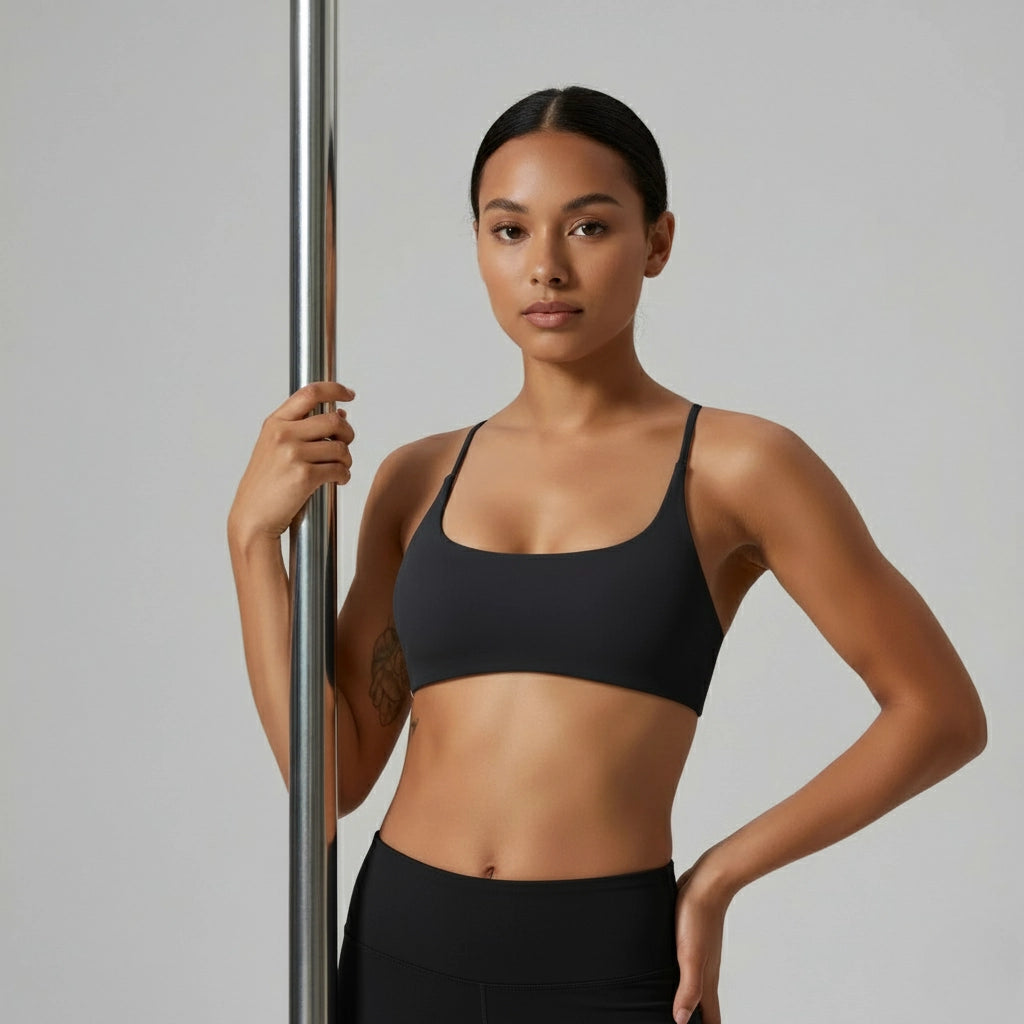 Femme tenant une barre de pole dance et portant une brassière de Pole Dance noire