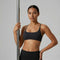 Femme tenant une barre de pole dance et portant une brassière de Pole Dance noire