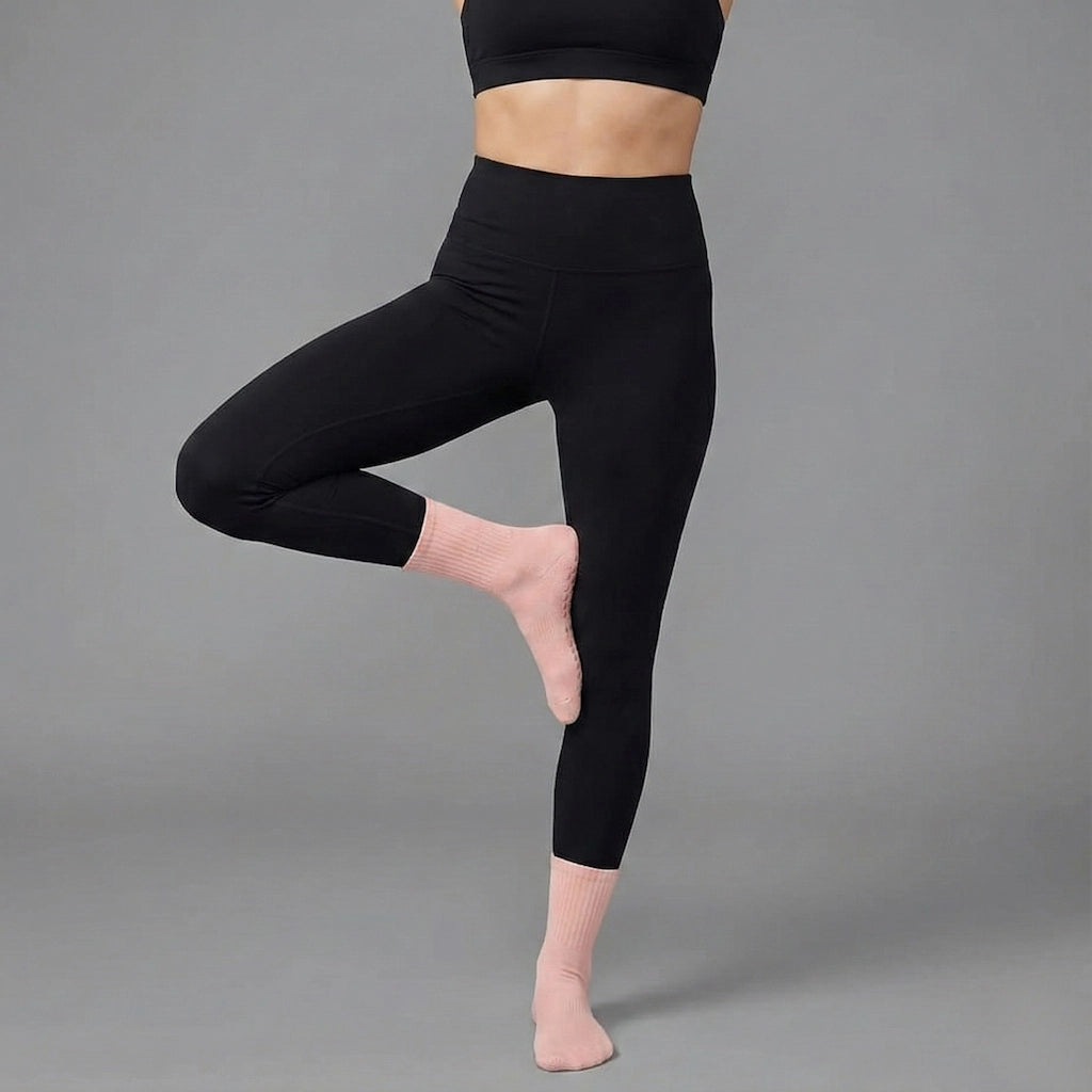 Femme portant des chaussettes longues antidérapantes pour le yoga de couleur rose