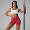 Femme tenant une barre de pole dance et portant un short de pole dance à taille haute évasée rouge